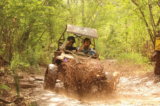 Un ATV side-by-side che schizza su una pista fangosa tra gli alberi