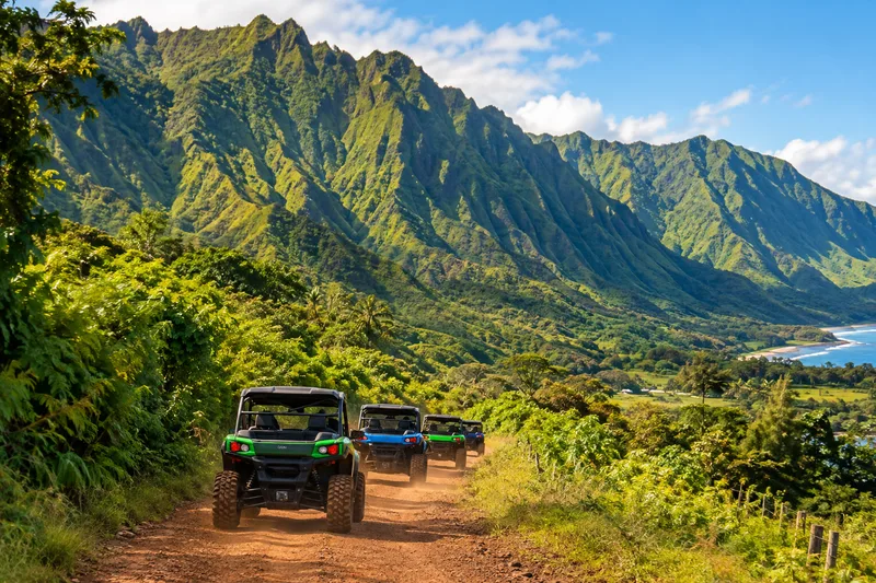 Un convoi d'UTV sur un chemin du ranch sous de hautes montagnes vertes