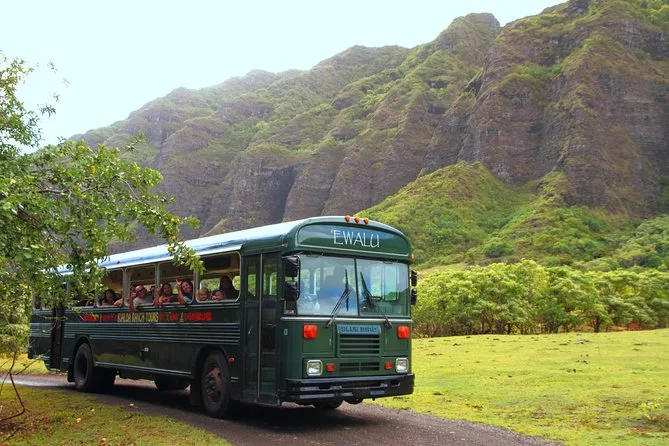 A vintage tour bus in a green valley at Kualoa Ranch