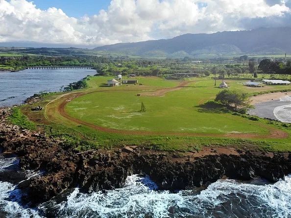 Vista aérea de campos, un camino de tierra roja y la costa de North Shore